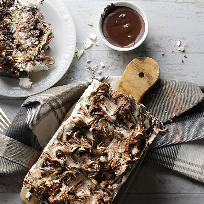 Photo of an almond joy-inspired brownie loaf served on a cutting board with chocolate meringue