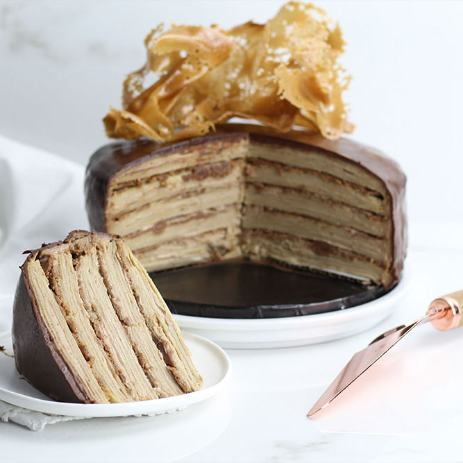 Photo of a large slice of "Kit Kat" inspired Crepe Cake, with layers of crepe, crémeux and chocolate ganache topped with bienetta.