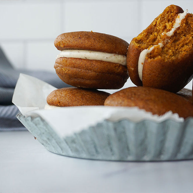 Photo of Pumpkin Spice Whoopie Pies in a silver pan with wax paper.