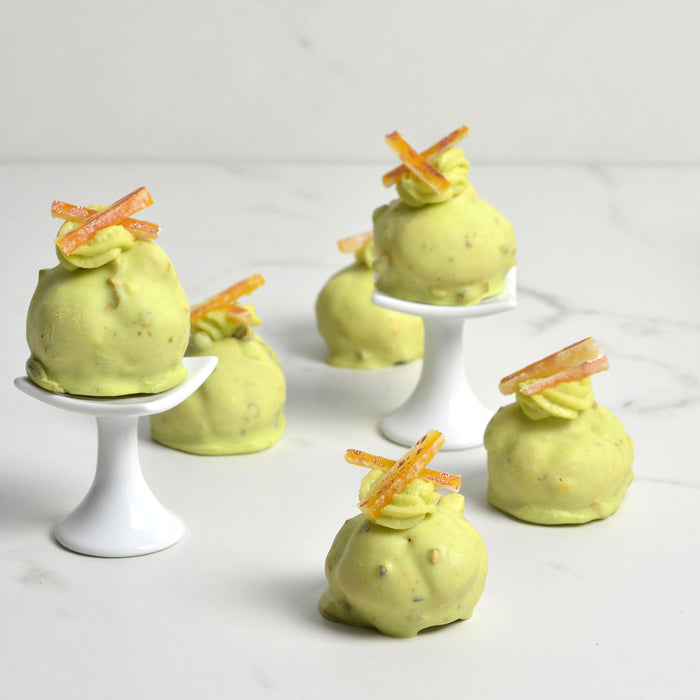 Cream Puffs with Pistachio flavored White Chocolate and Candied Orange Peel Decor