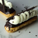 Vanilla Eclair topped with white frosting, dark chocolate pencil and chocolate mini stars